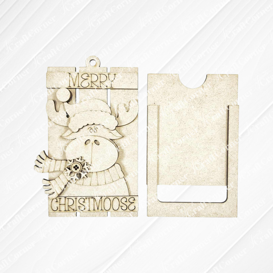 Janet's Craft Corner Forest Friends Ornaments DIY kit features two beige wooden cutouts: a cartoon moose with “Merry Christmoose” and a slotted rectangle—perfect for your own festive holiday creations!.