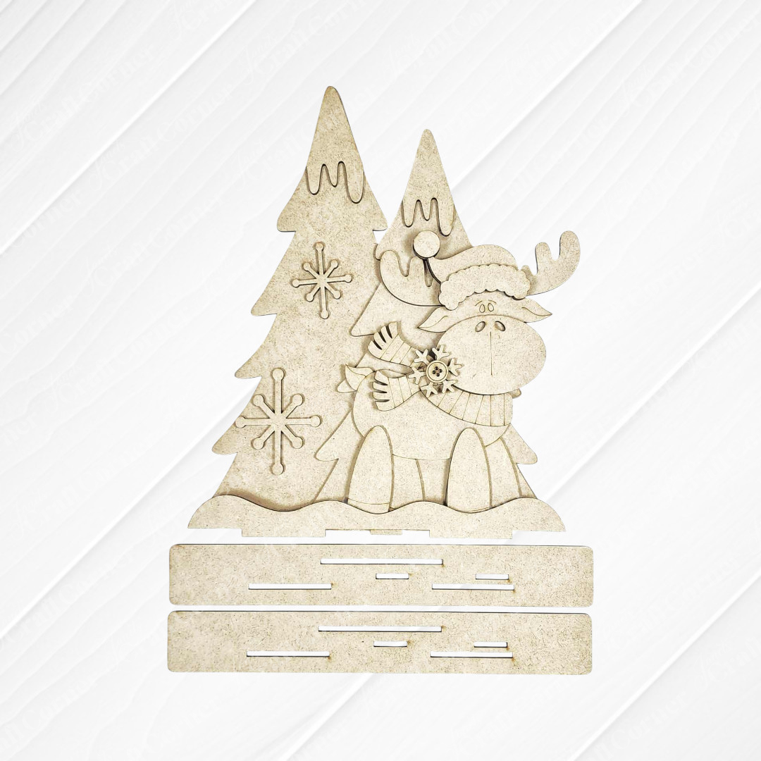 The "Moose with Trees Shelf Sitter" by Janet's Craft Corner features a cartoon moose in winter attire beside two festive trees—ideal as seasonal decor or a fun DIY craft kit for your home. Set of 1.