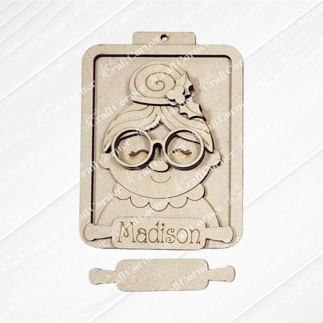 This festive Mrs. Claus ornament from Janet's Craft Corner features a cartoon grandmother with glasses and a bun, "Madison" engraved on a rolling pin, and a top hole for easy hanging with Santa ornaments on your tree.