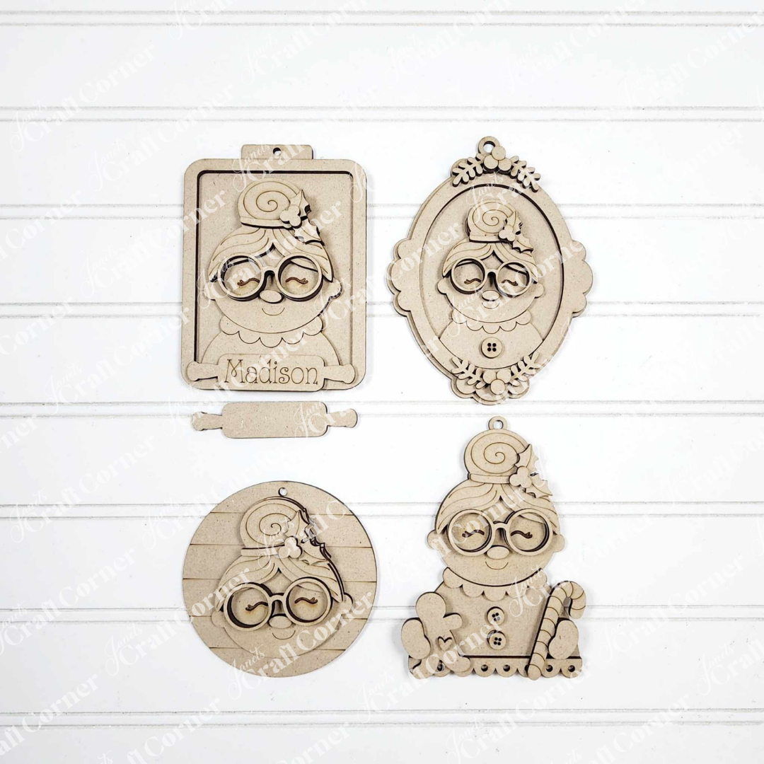 Set of four Mrs. Claus Ornaments from Janet's Craft Corner, each with glasses and a bun in assorted shapes (clipboard, oval frame, circle, candy cane stand). Ideal for festive decor or DIY crafts. One ornament labeled "Madison.