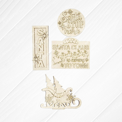 The North Pole Decor Set from Janet's Craft Corner features four wooden cutouts—“Santa” with snowflakes, “Santa Stop Here,” “Santa Claus is coming to town,” and a sleigh—perfect for festive DIY holiday decor.