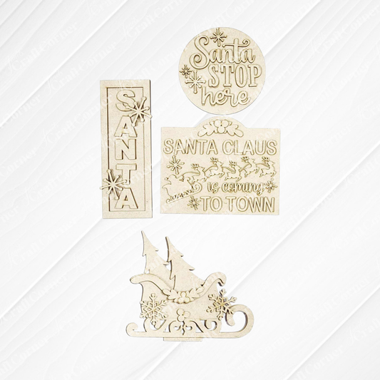 The North Pole Decor Set from Janet's Craft Corner features four wooden cutouts—“Santa” with snowflakes, “Santa Stop Here,” “Santa Claus is coming to town,” and a sleigh—perfect for festive DIY holiday decor.