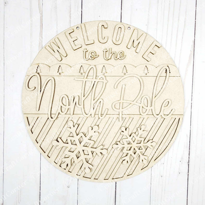 Janet's Craft Corner North Pole Door/Wall Hanger DIY kit includes a round sign with cutout "Welcome to the North Pole" letters, snowflakes, and diagonal stripes—perfect for festive seasonal home decor. Set of 1.