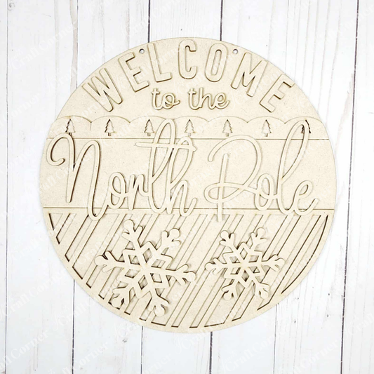 Janet's Craft Corner North Pole Door/Wall Hanger DIY kit includes a round sign with cutout "Welcome to the North Pole" letters, snowflakes, and diagonal stripes—perfect for festive seasonal home decor. Set of 1.
