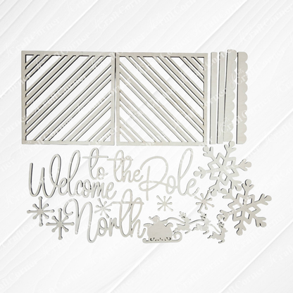 Janet's Craft Corner North Pole Porch Leaner DIY kit includes metal dies for holiday decor, featuring striped rectangles, scalloped edges, snowflakes, a sleigh with reindeer, and "Welcome to the North Pole" script. Set of 1.