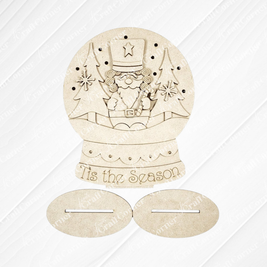 Add a festive touch to your home with Janet’s Craft Corner’s Nutcracker Light-Up Snow Globe Shelf Sitter. This DIY home decor craft kit features a wooden ornament shaped like a snow globe, showcasing a nutcracker between two trees and engraved with “’Tis the Season” at the base. Complete with two oval wooden stands below the globe, this charming set of one is perfect for holiday shelf displays.