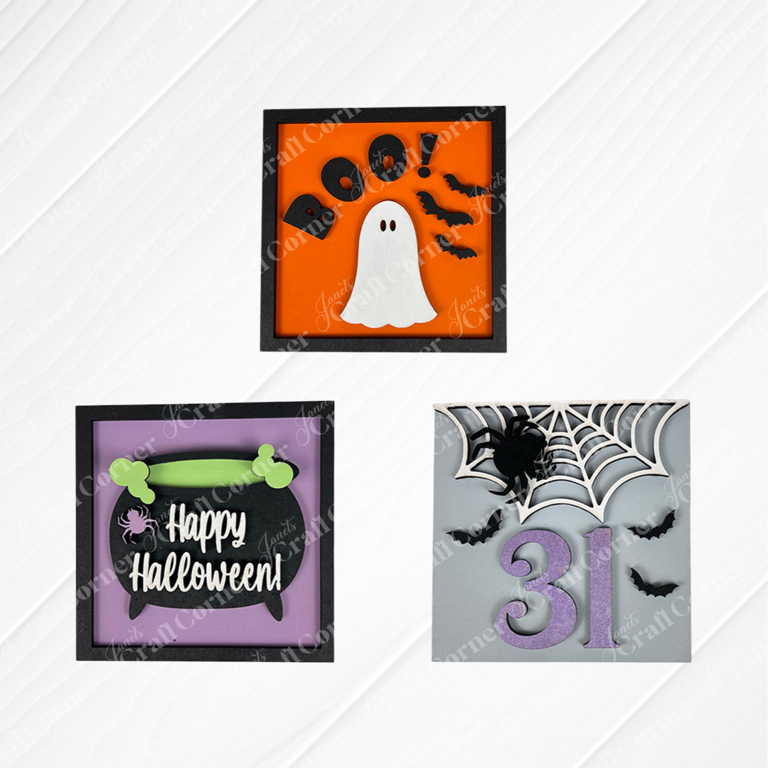 Janet's Craft Corner "Oct 31 Squares" features three square Halloween cookies for tray decor: a ghost with "BOO!" and bats, a purple cauldron with "Happy Halloween," and a web with spider, bats, and "31" on white textured backgrounds.