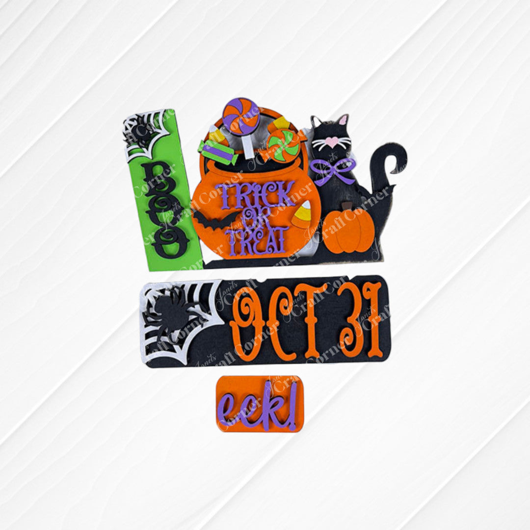 Janet's Craft Corner's Oct 31 Interchangeable Insert DIY home decor kit features Halloween-themed designs, including a hand-painted tombstone with "BOO" and a pumpkin with "TRICK OR TREAT," all artfully arranged on a textured white surface, creating a delightful display reminiscent of interchangeable home decor sets.
