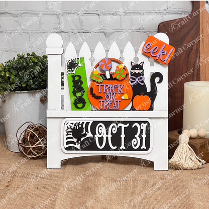 Janet's Craft Corner offers a Garden Fence with Insert, featuring a wooden Halloween-themed design adorned with "Boo," "Trick or Treat" signs, a black cat, pumpkin, lollipops, and spider web against a white brick wall—perfect for festive home decor.