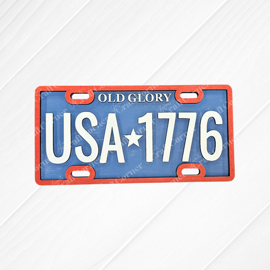 The Old Glory License Plate Shelf Leaner from Janet's Craft Corner is a DIY home decor craft kit featuring "OLD GLORY" and "USA★1776" on a red-bordered, blue background—perfect for farmhouse or patriotic themes. Set of 1.
