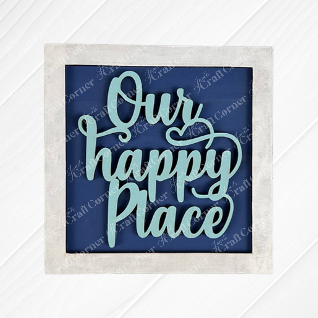 The Home Squares sign from Janet's Craft Corner features "Our happy place" in large, cursive light blue letters on a blue background—ideal as tiered tray decor or paired with wood cut-outs to add a cozy touch.