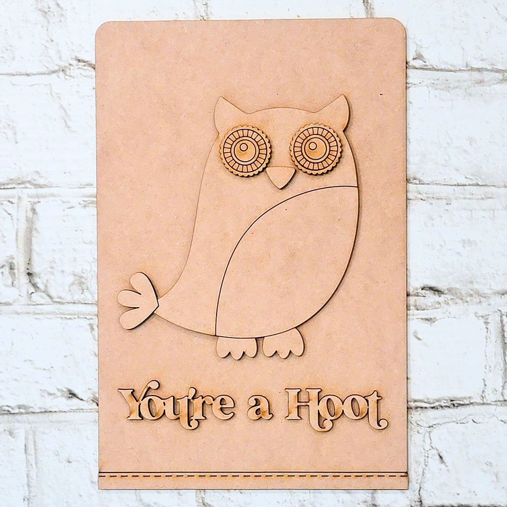 The "You're a Hoot" Tea Towel from Janet's Craft Corner is a delightful DIY home decor kit that features a carved owl illustration alongside the engraved text "You're a Hoot." Perfect for adding rustic charm to your space, this tea towel can be beautifully displayed against a textured white brick wall for those who love unique craft projects.