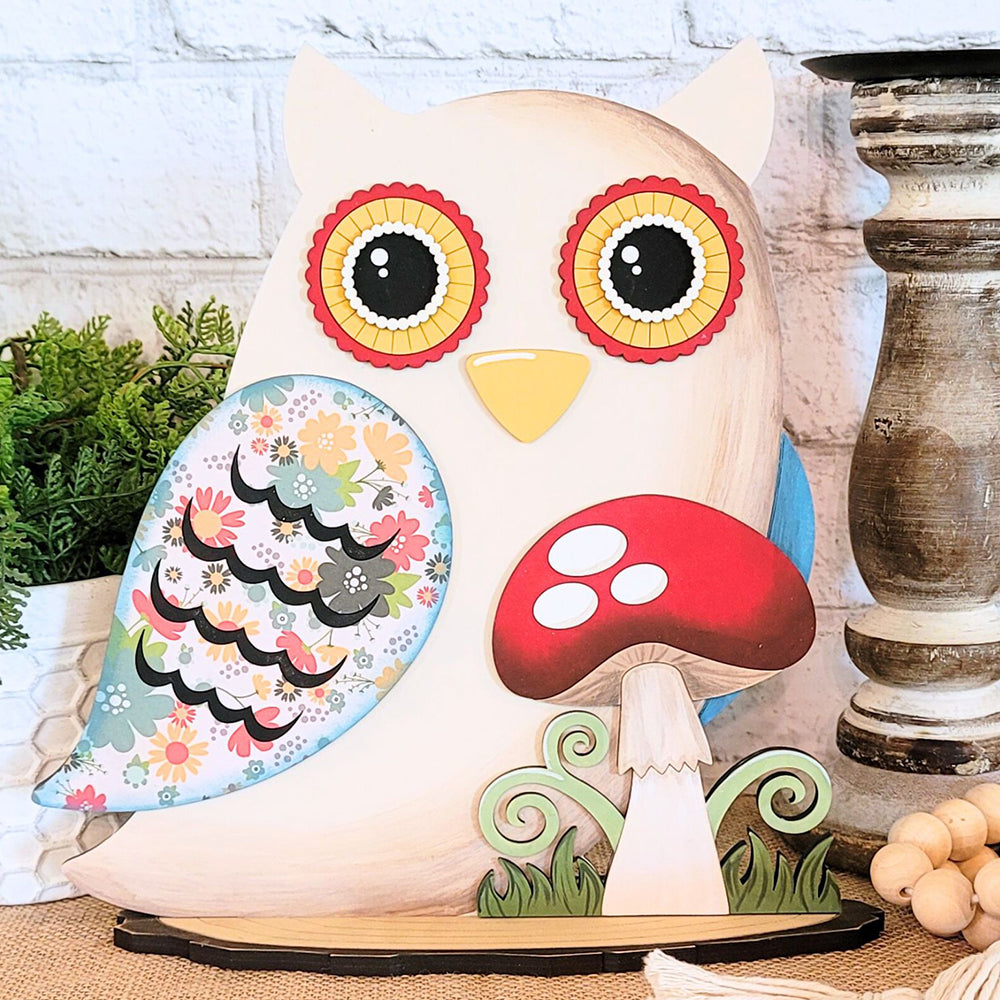 The Owl with Mushroom DIY home decor kit from Janet's Craft Corner includes a charming, hand-painted owl art piece with vibrant eyes and flower-patterned wings. Accompanied by a red-capped mushroom ornament, this kit adds nature-inspired beauty against a white brick background to your home decor. Ideal for anyone who appreciates unique DIY crafts.