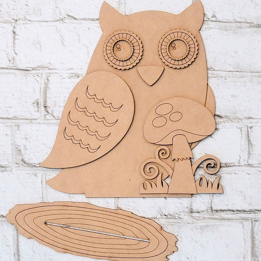 Explore the Owl with Mushroom DIY home decor kit by Janet's Craft Corner, a wooden masterpiece featuring intricate patterns, decorative swirls, and an enchanting mushroom element. Ideal for home decoration, its pieces elegantly lie on a white brick surface, encouraging creativity with every hand-painted assembly.