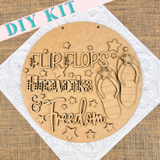 This Americana-inspired Patriotic Flip Flops Door Hanger from Janet's Craft Corner features laser-cut text and images that read "Flip Flops, Fireworks & Freedom" with star and flip-flop cutouts. It is set against a burlap background and includes a "DIY KIT" at the top for easy assembly.