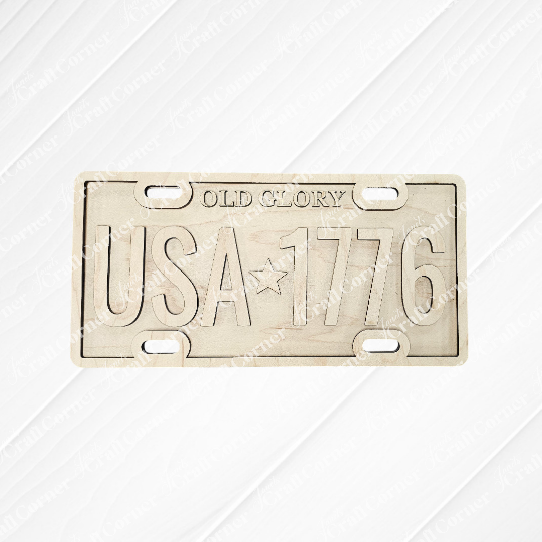 The Old Glory License Plate Shelf Leaner from Janet's Craft Corner is a DIY home decor craft kit featuring "OLD GLORY" and "USA ★ 1776" on a metal plate—perfect for adding farmhouse flair or as a creative project for your space.