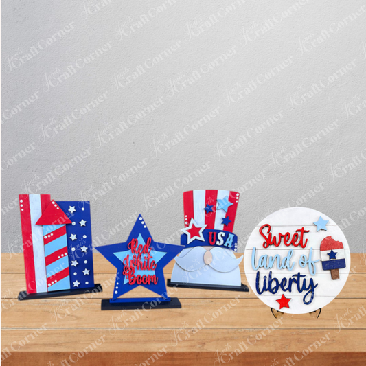 Janet's Craft Corner’s Patriotic Mini Shelf Sitters – DIY Craft Kit includes four Americana-themed pieces: a striped rectangle, “Red, White & Boom” star, “Sweet land of liberty” round sign, and a “USA” hat with balloons.