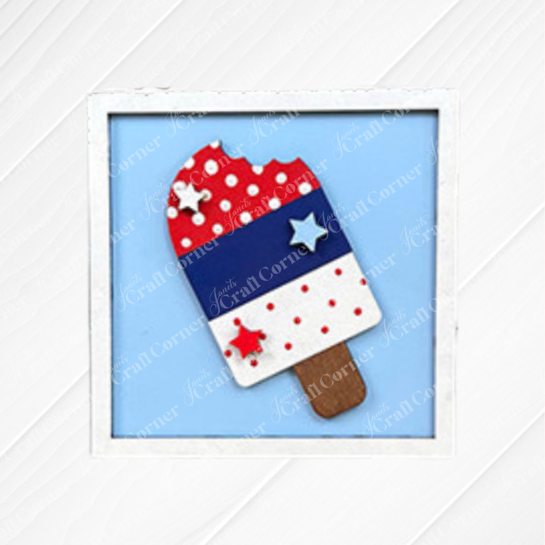 Display the "Patriotic Squares - DIY seasonal home decor craft kit" by Janet's Craft Corner—a framed popsicle-shaped decoration in red, white, and blue with stars and polka dots on a light blue background. Ideal for Independence Day crafts!.