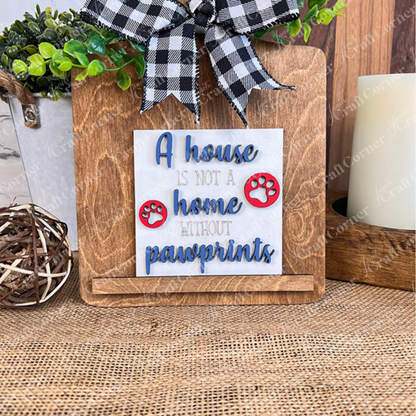 The Dog Squares by Janet's Craft Corner is a wooden sign with wood cut-outs, a plaid bow, and a Swappable Square tile reading "A house is not a home without pawprints" with red paw prints. Ideal tiered tray decor for dog lovers.