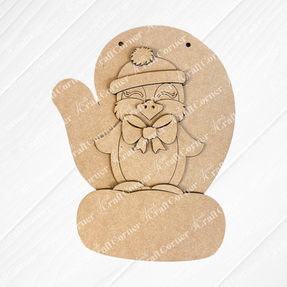 The Penguin Mitten Sign from Janet's Craft Corner showcases a penguin shape with a hat and bow, set on a textured white mat over burlap. It's perfect for DIY kit enthusiasts wanting to personalize their home décor with charming flair.