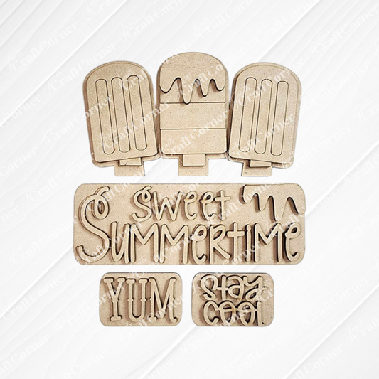 Wooden cutouts of three popsicles, decorated with phrases such as "Sweet Summertime," "Yum," and "Stay Cool" in fun, wavy fonts on a white background. This DIY home decor kit from Janet's Craft Corner is perfect for creating delightful decorations or an enchanting interchangeable insert.