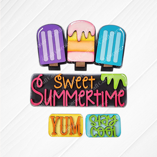 The Popsicle Interchangeable Insert from Janet's Craft Corner, a DIY home decor kit, features colorful popsicle decorations and includes a sign with "sweet summertime" in pink letters. Below it, two smaller signs proclaim "YUM" in orange and "STAY COOL" in green, all beautifully set against a white wooden surface to enhance this charming piece.
