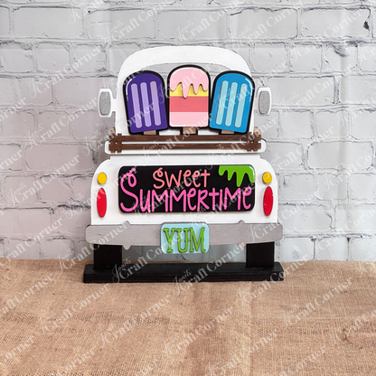 Add a charming touch to your home décor with Janet's Craft Corner's DIY home decor kit, featuring the Popsicle Interchangeable Insert. This decorative piece showcases a white truck with vibrant popsicles and "Sweet Summertime" elegantly written in pink and orange above a teal "YUM" license plate. It's perfect standing in front of a white brick wall.