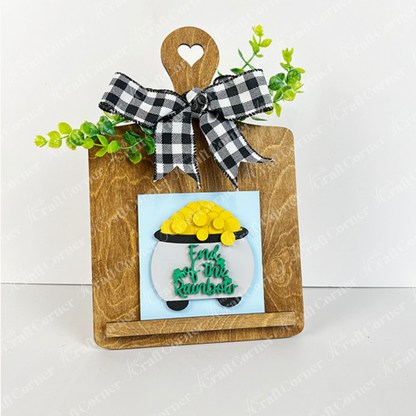 Janet's Craft Corner St Patricks Squares: A wooden decor board with a heart cutout, black-and-white gingham bow, faux greenery, and "End of the Rainbow" pot of gold—perfect for tiered trays or pairing with wood cut-outs.