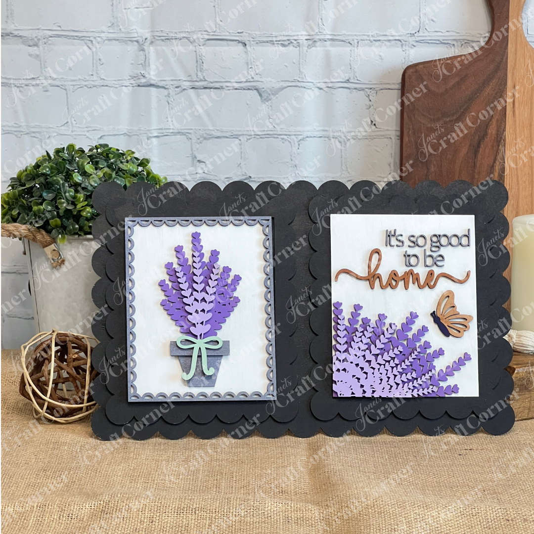The Lavender Switchable Farmhouse Signs DIY Craft Kit by Janet's Craft Corner features a black scalloped frame with two panels—a bouquet of purple flowers in a jar, and layered blooms with “It’s so good to be home”—for charming tiered tray décor.