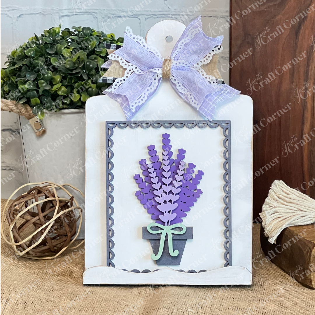 The Lavender Switchable Farmhouse Signs – DIY Craft Kit from Janet's Craft Corner features a white scalloped plaque with paper lavender, finished with a lace and burlap bow—ideal for tiered trays or rustic farmhouse décor.