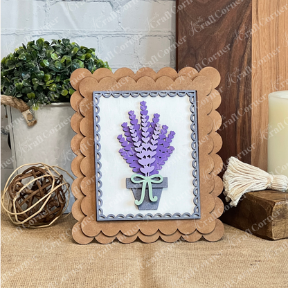 Janet's Craft Corner Lavender Switchable Farmhouse Signs – DIY Craft Kit features 3D paper lavender in a gray pot with a green bow on burlap, perfect for tiered tray décor. Scene includes a potted plant, woven ball, candle, and tassel accents.