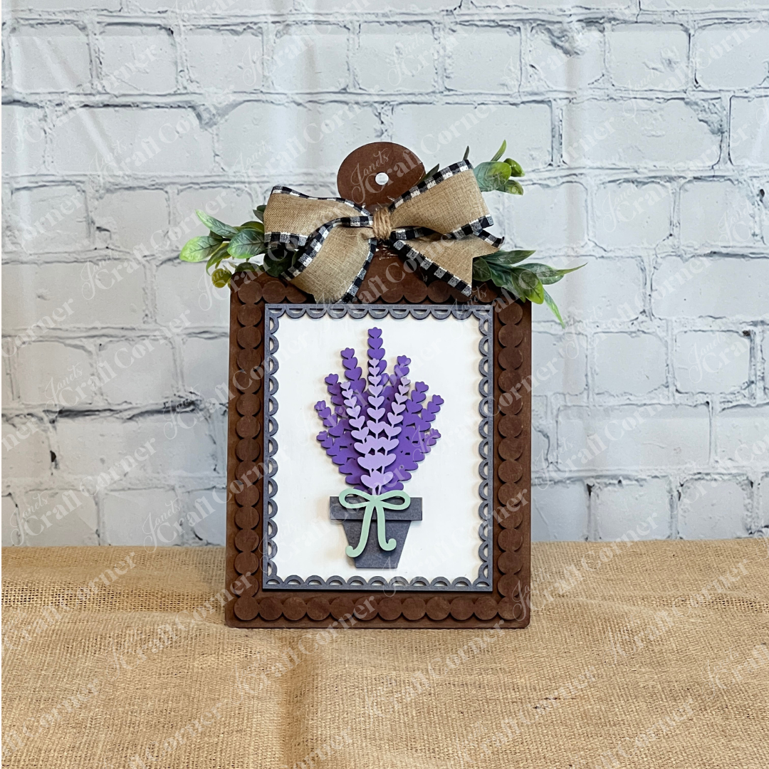 The Lavender Switchable Farmhouse Signs DIY Craft Kit by Janet's Craft Corner includes a wooden plaque with scalloped border, 3D paper bouquet in a pot, green ribbon, and burlap plaid bow—perfect for tiered tray décor.
