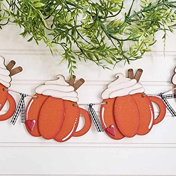 The Pumpkin Spice Banner by Janet's Craft Corner is a charming DIY home decor kit featuring adorable, orange pumpkin-shaped decorations accented with whipped cream and cinnamon sticks. Green leaves and checkered ribbon ties elegantly strung across the top complete this festive banner, making it a delightful addition to your home decor.