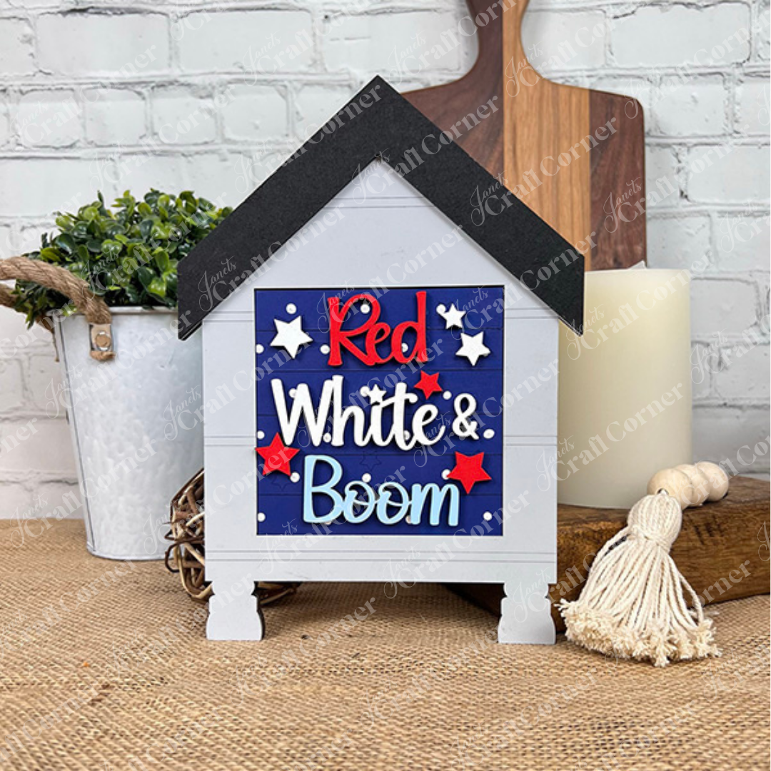The Patriotic Squares DIY kit by Janet's Craft Corner features a small wooden house sign with “Red White & Boom” in red, white, and blue plus stars—ideal Independence Day décor for your table.