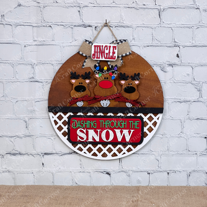 Add festive cheer with Janet's Craft Corner's Reindeer Interchangeable Insert. This DIY seasonal home decor kit features hand-painted reindeer with red noses and scarves, a plaid "Jingle" sign above, and "Dashing Through the Snow" below, set against a white brick wall.