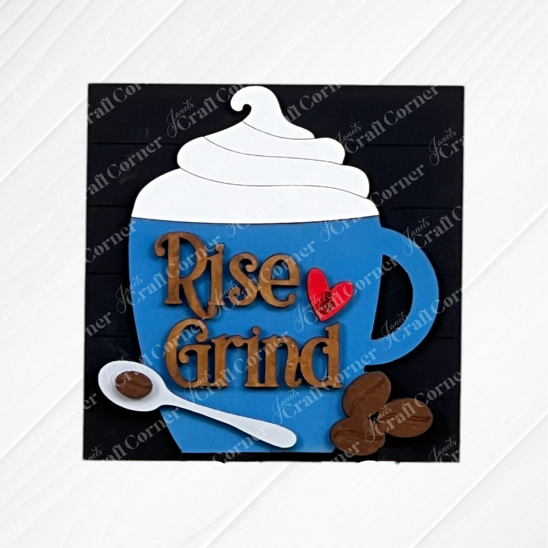 The Coffee Swappable Squares DIY seasonal home decor craft kit by Janet's Craft Corner features a blue coffee mug sign with whipped cream, "Rise & Grind" text, and a red heart—perfect decor for coffee lovers-displayed on a white wood background.