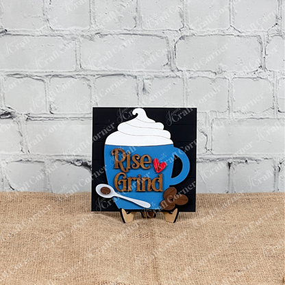 The Coffee Swappable Squares DIY seasonal home decor craft kit by Janet's Craft Corner features a blue coffee mug sign with whipped cream, "Rise & Grind" text, and a red heart—perfect decor for coffee lovers.