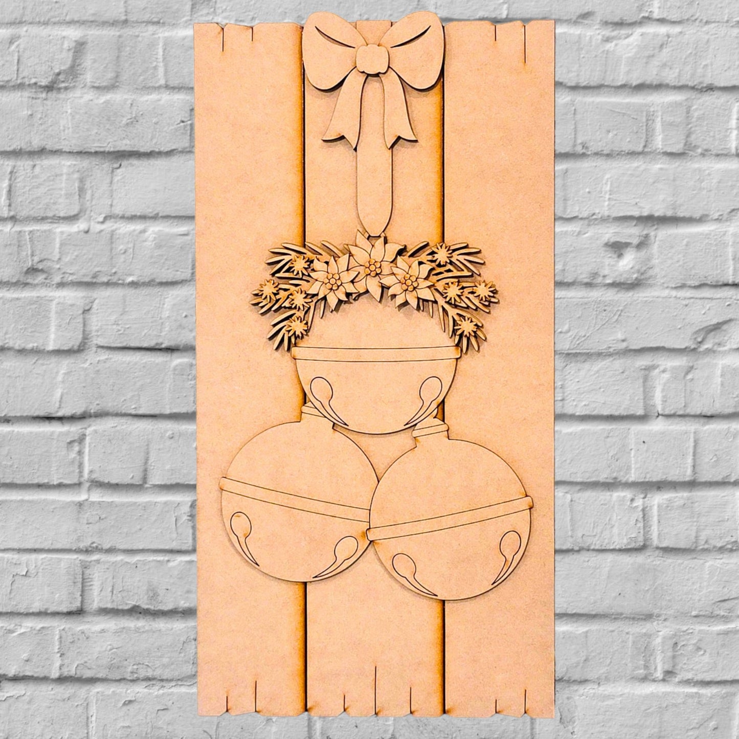 Introducing Janet's Craft Corner Rustic Bell Cluster Leaner, a DIY Home Decor Kit made from reclaimed barn wood. This charming piece showcases three intricately carved jingle bells adorned with lush foliage and topped off with a decorative ribbon, all beautifully set against a brick wall backdrop.