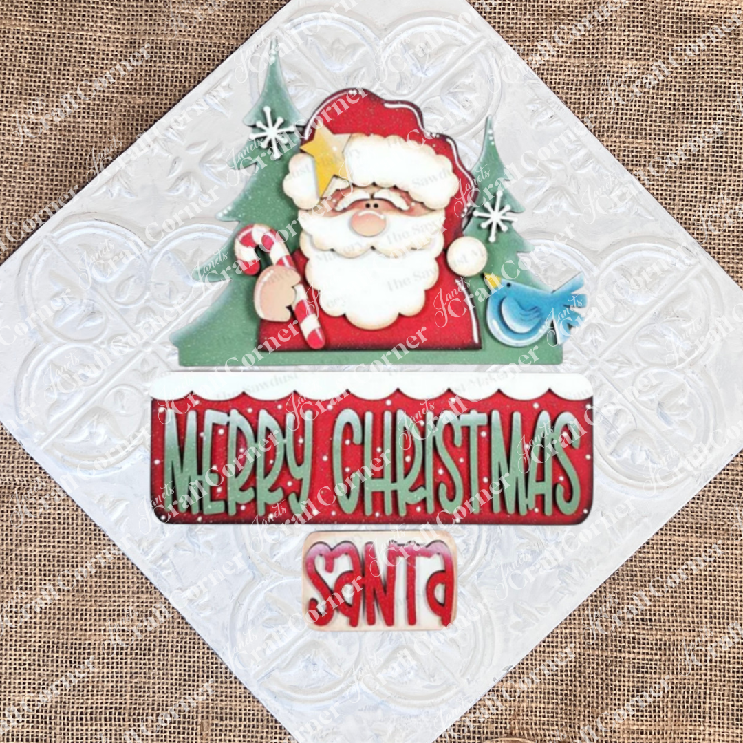 Janet's Craft Corner Santa Merry Christmas Interchangeable Insert DIY kit features a smiling Santa with a candy cane, vibrant "Merry Christmas" lettering, and festive trees—perfect for seasonal home decor and holiday crafts. Set includes 3 pieces.