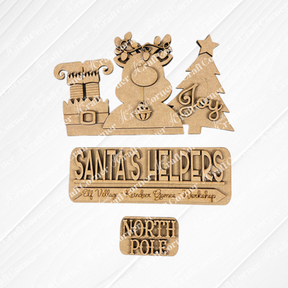 Janet's Craft Corner presents the "Santa's Helpers Interchangeable Insert" DIY home décor kit, showcasing wooden cutouts on a textured background to bring charm to your holiday scene. It features a chimney, an antlered snowman, and a tree with the word "Joy," along with signs reading "Santa's Helpers" and "North Pole." This kit is perfect for festive creativity with its interchangeable inserts.