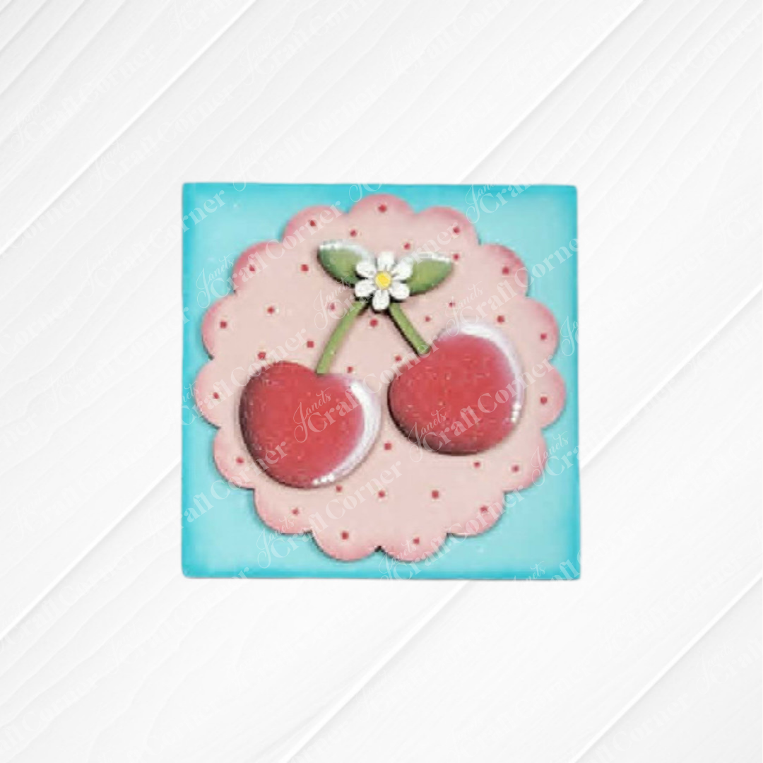 Add a playful touch to your home with Janet's Craft Corner Cherry Squares—a DIY kit featuring a square wood cut-out tile with red cherries, green leaves, and a white flower on a pink scalloped circle—ideal for Swappable Squares or tray displays.