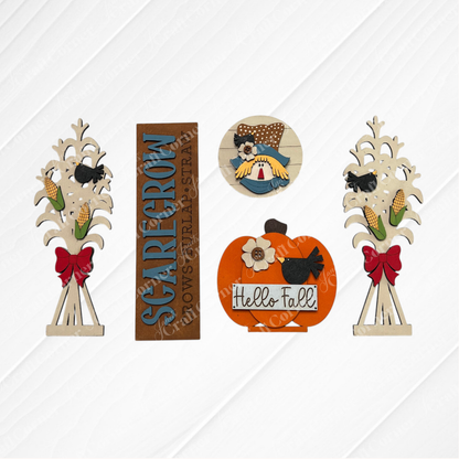 Janet's Craft Corner's Scarecrow Interchangeable Porch Set includes five autumn-themed wooden decorations—corn stalk insert, "Scarecrow" sign, chicken on eggs, pumpkin greeting, and crow—ideal for DIY seasonal home decor. Displayed on a white background.