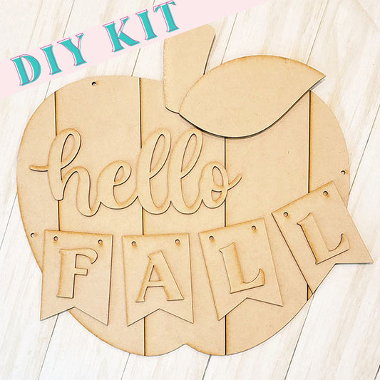 Introducing the Shiplap Apple Door Hanger from Janet's Craft Corner. This DIY Kit features an apple-shaped wooden sign with cut-out letters that spell "hello FALL," perfect for adding a seasonal touch to your home décor on a light wooden background.