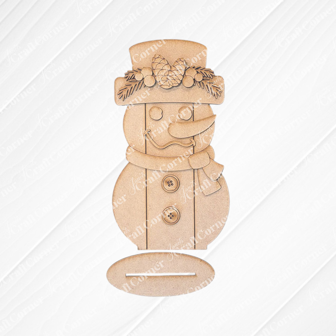 Introducing Janet's Craft Corner Shiplap Snowman Shelf Sitter, a DIY seasonal home decor kit. This wooden cutout snowman is adorned with pinecone and leaf embellishments, featuring a charming hat, scarf, buttons, and classic carrot nose on a textured wooden backdrop.