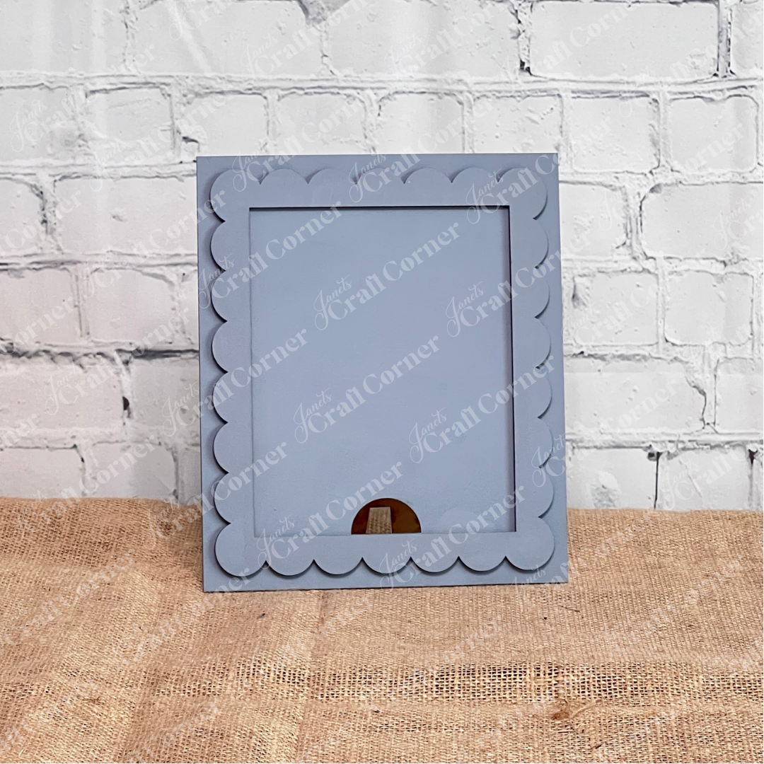 The Single Scallop Trim Farmhouse Frame by Janet's Craft Corner features a light gray, scalloped-edge design—ideal for DIY craft lovers seeking a decorative, interchangeable display for their favorite photos or artwork.