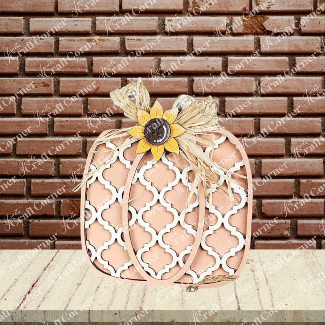 The Fall Harvest Mini Shelf Sitters DIY craft kit by Janet's Craft Corner features a beige and white lattice pumpkin with sunflower and raffia bow—perfect autumn decor for your home. Set of 1. Displayed in front of a red brick wall and light wood surface.