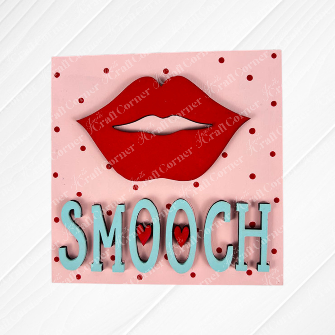 Love Squares by Janet's Craft Corner is a pink square tiered tray sign featuring red lips above “SMOOCH” in blue with red dots and two small hearts inside the “O”—a perfect DIY craft kit for your seasonal decor.