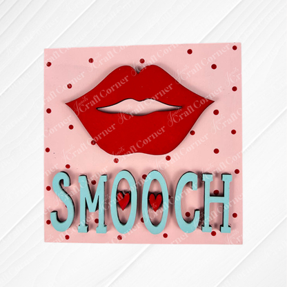 Love Squares by Janet's Craft Corner is a pink square tiered tray sign featuring red lips above “SMOOCH” in blue with red dots and two small hearts inside the “O”—a perfect DIY craft kit for your seasonal decor.