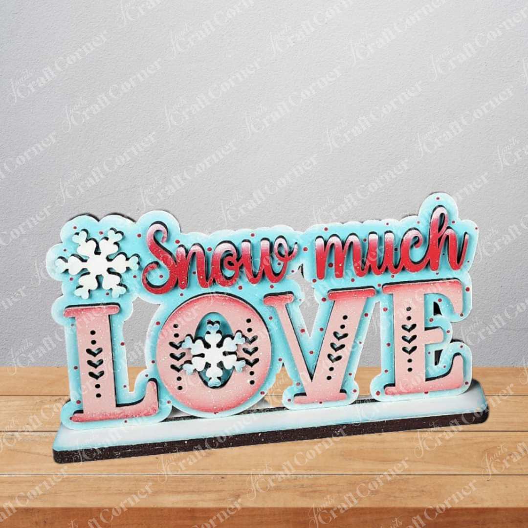The Valentine Snowmen Decor Set from Janet's Craft Corner is a DIY seasonal home decor craft kit with a "Snow much LOVE" sign in red and blue, accented with snowflakes—ideal to pair with your favorite snowman shelf sitter or wood cut-outs.