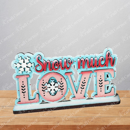 The Valentine Snowmen Decor Set from Janet's Craft Corner is a DIY seasonal home decor craft kit with a "Snow much LOVE" sign in red and blue, accented with snowflakes—ideal to pair with your favorite snowman shelf sitter or wood cut-outs.